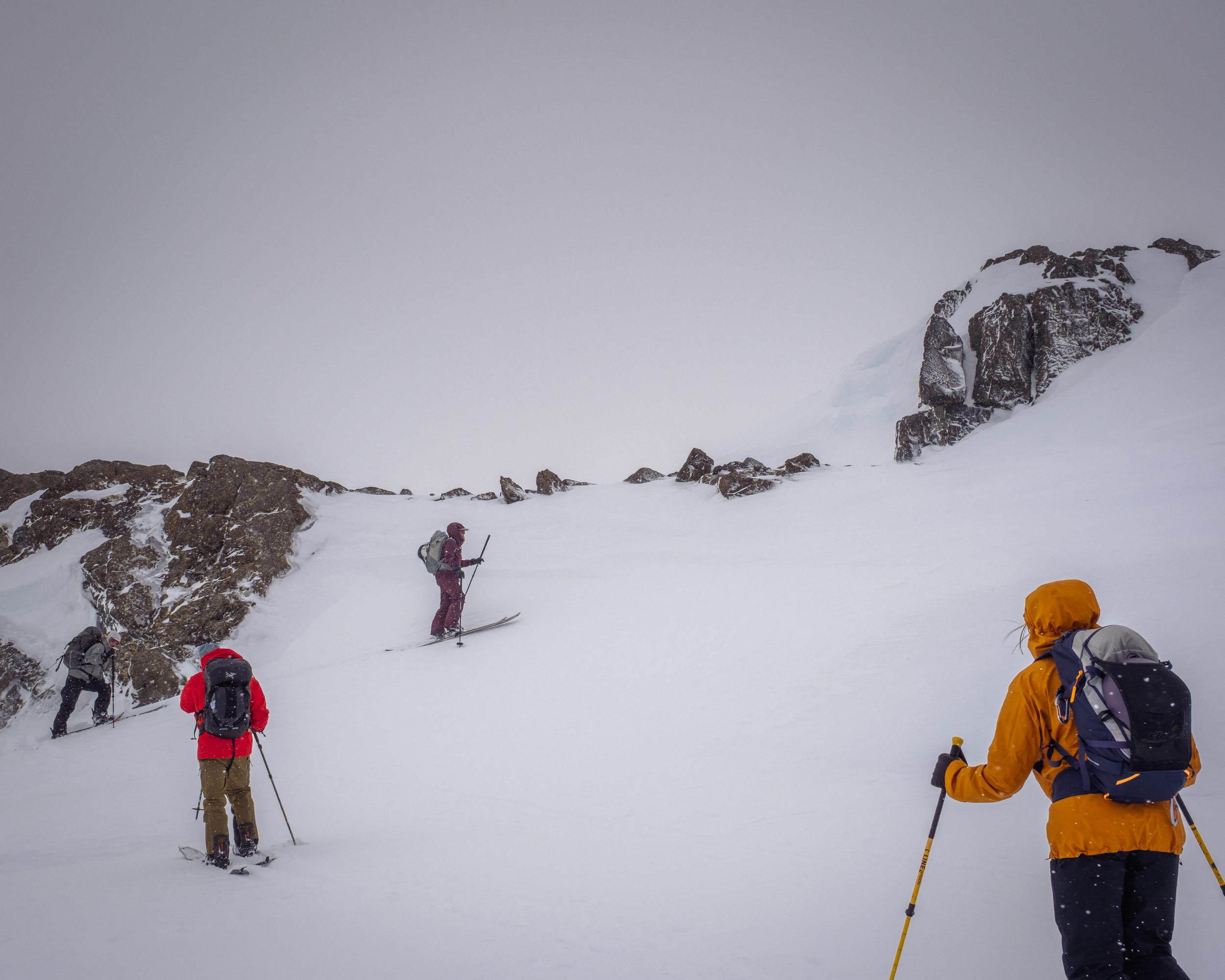 Three skinners working through flat-light snowfall